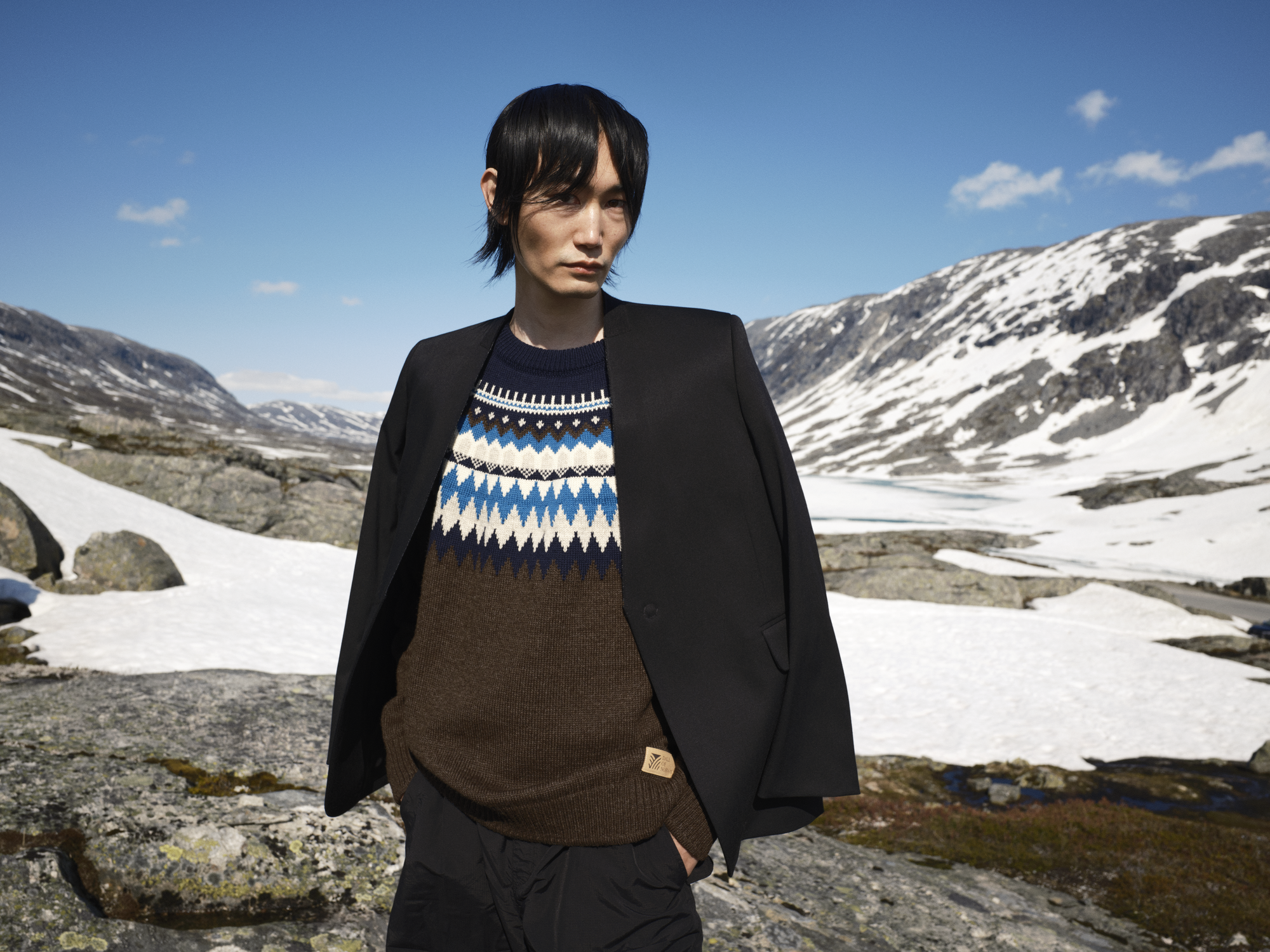 Male model wearing a brown wool sweater from Dale of Norway standing in Norwegian mountain 