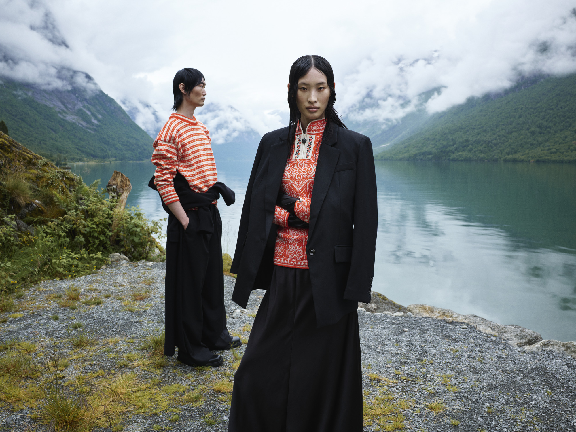 Two female models standing by the Norwegian fjord wearing wool sweaters